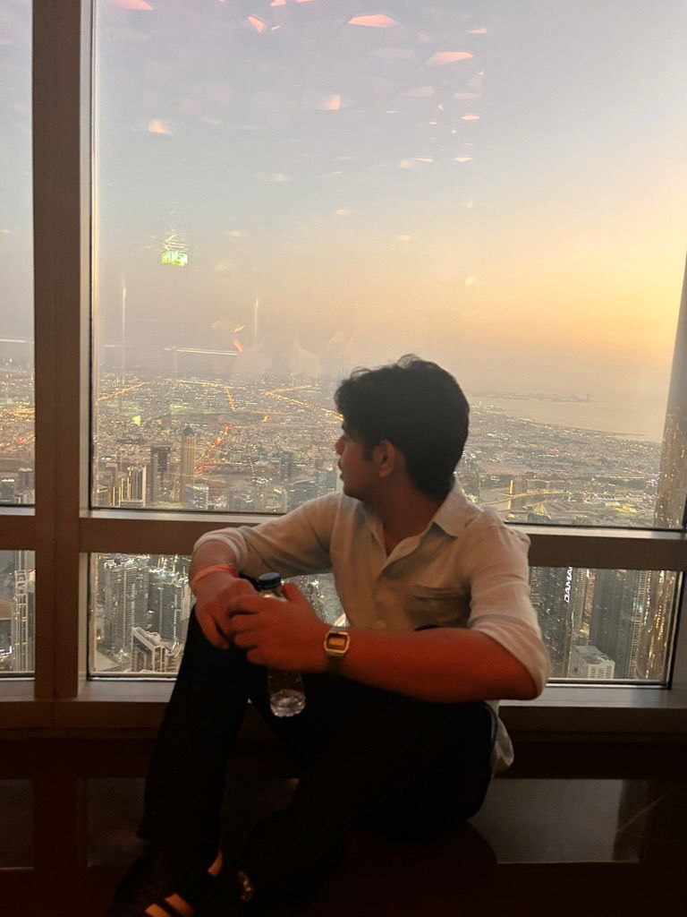 Seated at a high window above a city at dusk