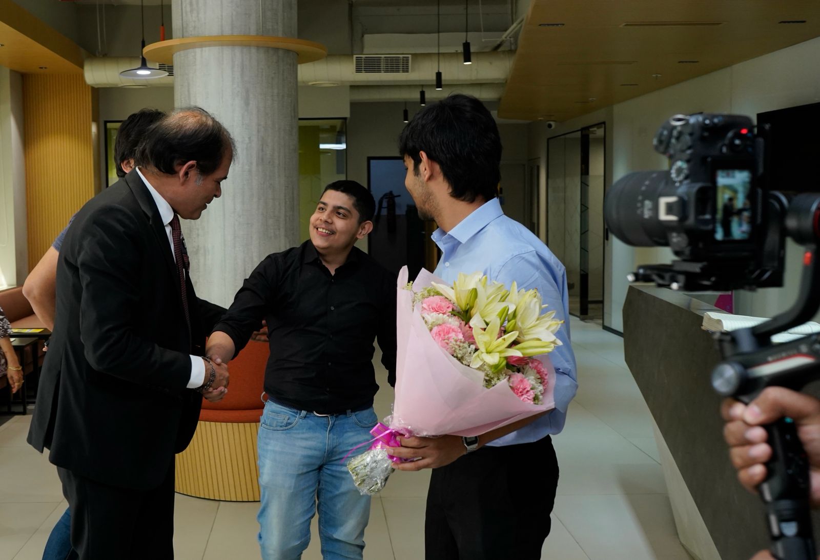 Greeting a guest with flowers at an office reception, being filmed